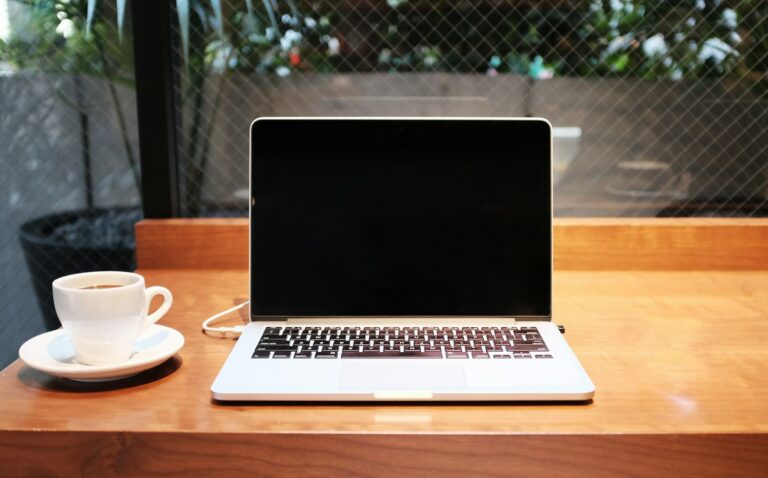 Laptop neben Kaffeetasse auf einem Schreibtisch